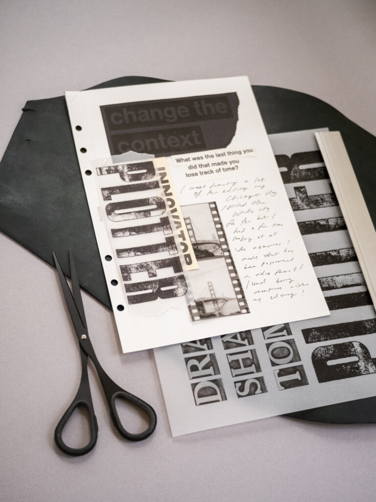 A collage on white paper with black and white graphics and pictures which is on top of a leather mat and a grey table.