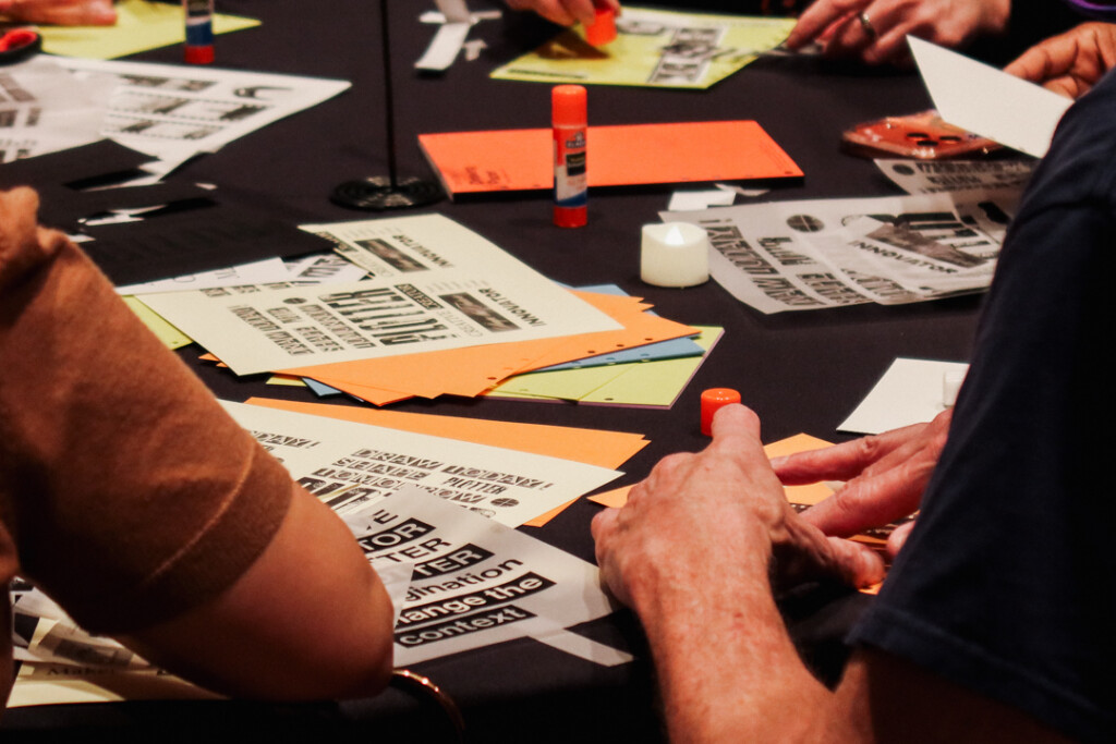 People collaging on a round table filled with paper supplies and glue.