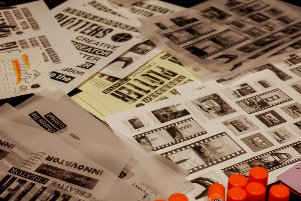A close-up of different collage materials, papers, and ephemera on a black table.
