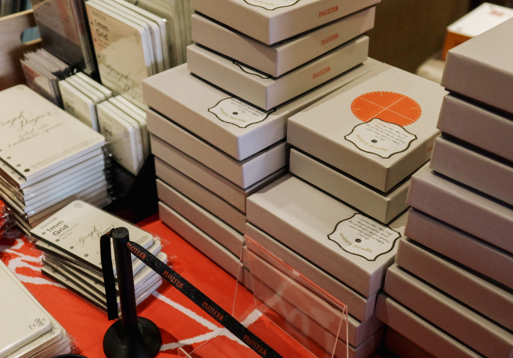 Stacks of grey PLOTTER boxes filled with Leather Binders in various sizes.