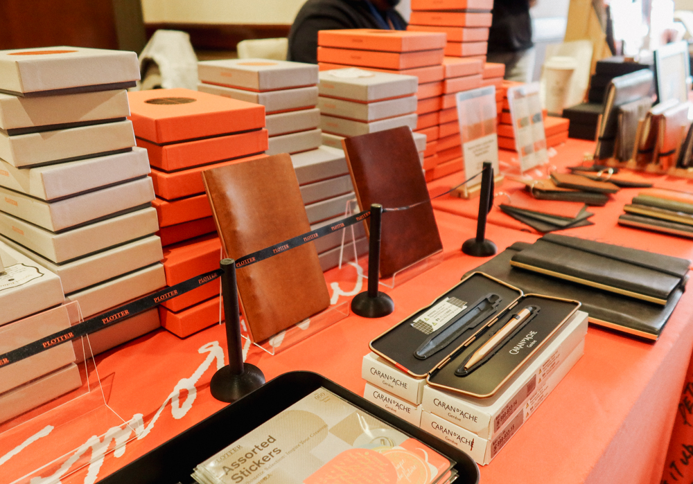 PLOTTER USA table filled with PLOTTER items, leather binders, and stationery at San Francisco Stationery Fest.
