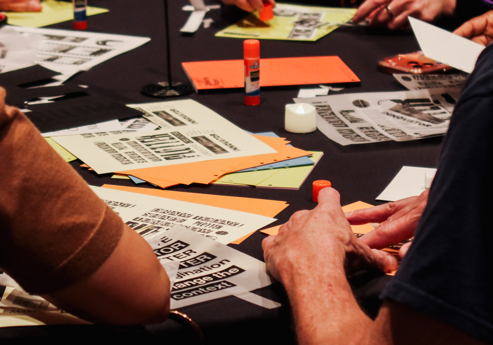 People collaging on a round table filled with paper supplies and glue.