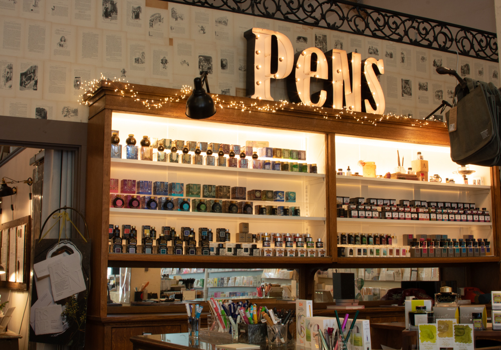 Interior of Oblation Papers and Press shop in Portland, Oregon, which has a fountain pen ink wall which features different fountain pens and inks on a wooden display case.