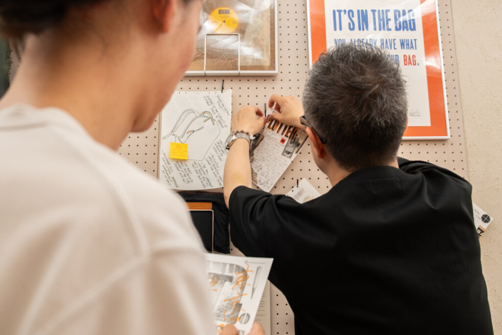 Takayuki Saito, the director of PLOTTER, is hanging completed collages on a peg board on the third floor of PLOTTER TOKYO.