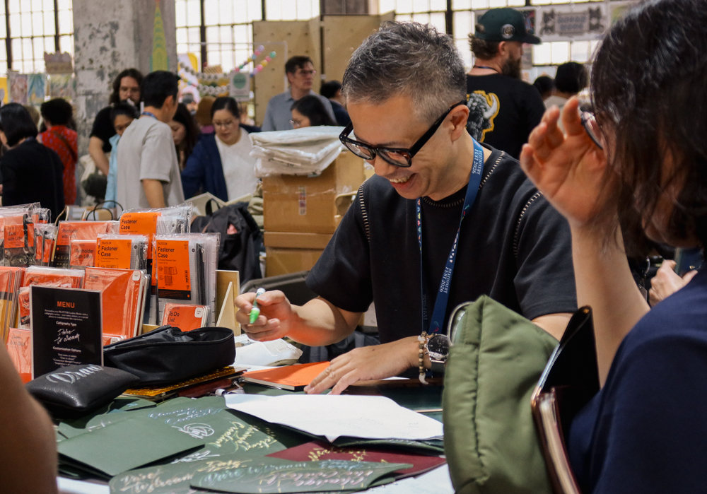 Takayuki Saito, the director of PLOTTER doing hand lettering and calligraphy on PLOTTER leather goods.