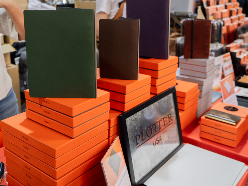 A large stack of PLOTTER boxes with leather binders on top of it.