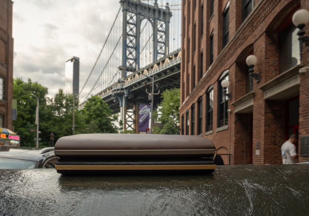 Two PLOTTER leather binders resting on a mailbox with the Manhattan Bridge in the background.