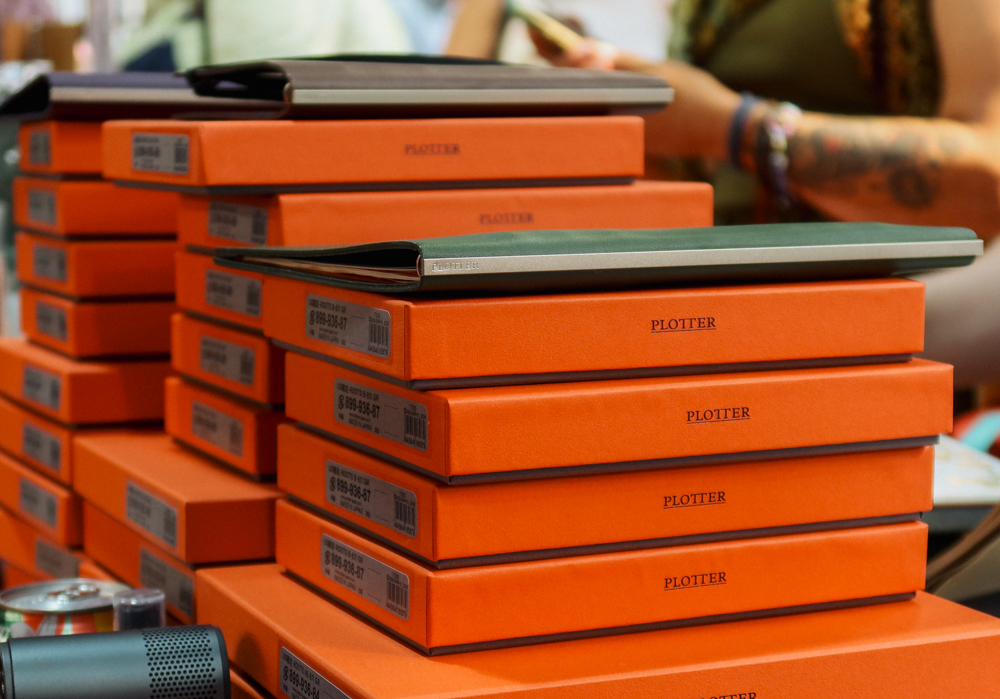 A large stack of PLOTTER boxes with leather binders on top of it.