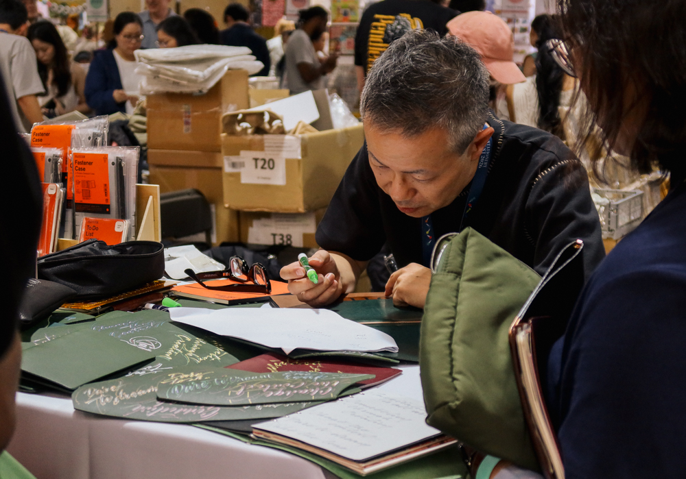 Takayuki Saito, the director of PLOTTER doing hand lettering and calligraphy on PLOTTER leather goods.