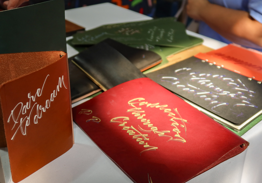 Examples of Takayuki Saito's hand lettering and calligraphy on PLOTTER leather goods.