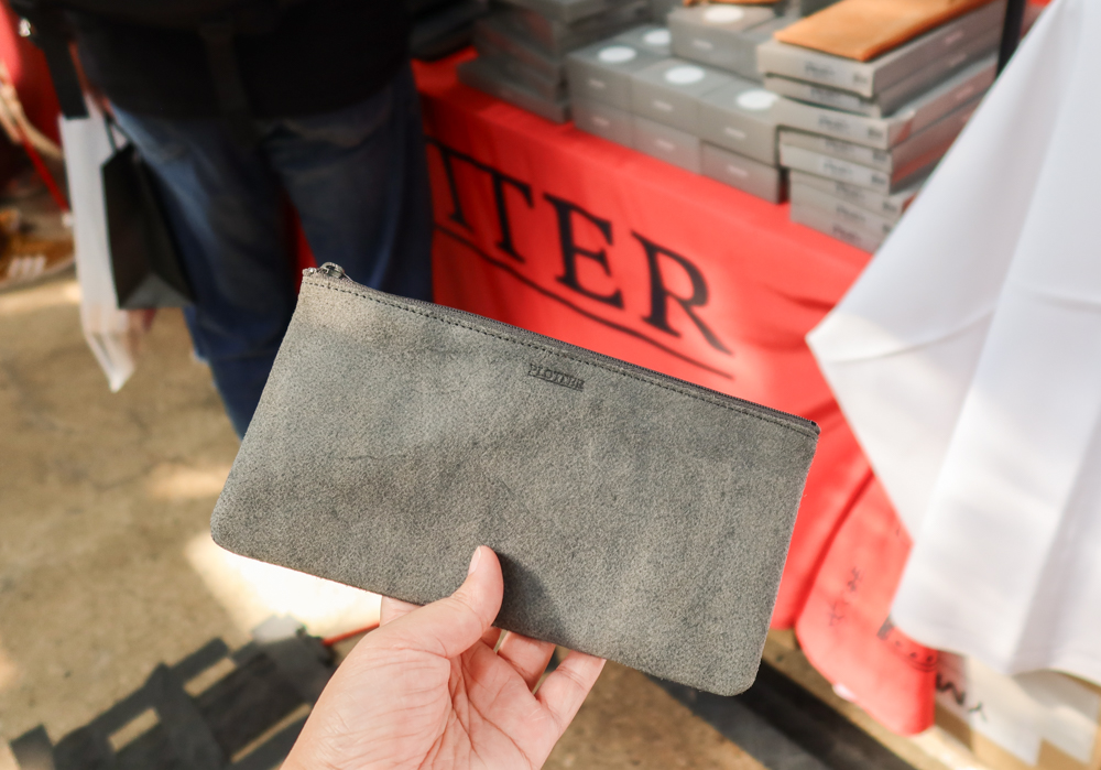 A person holding the black flat pen case in front of the PLOTTER USA table at Stationery Fest 2026.