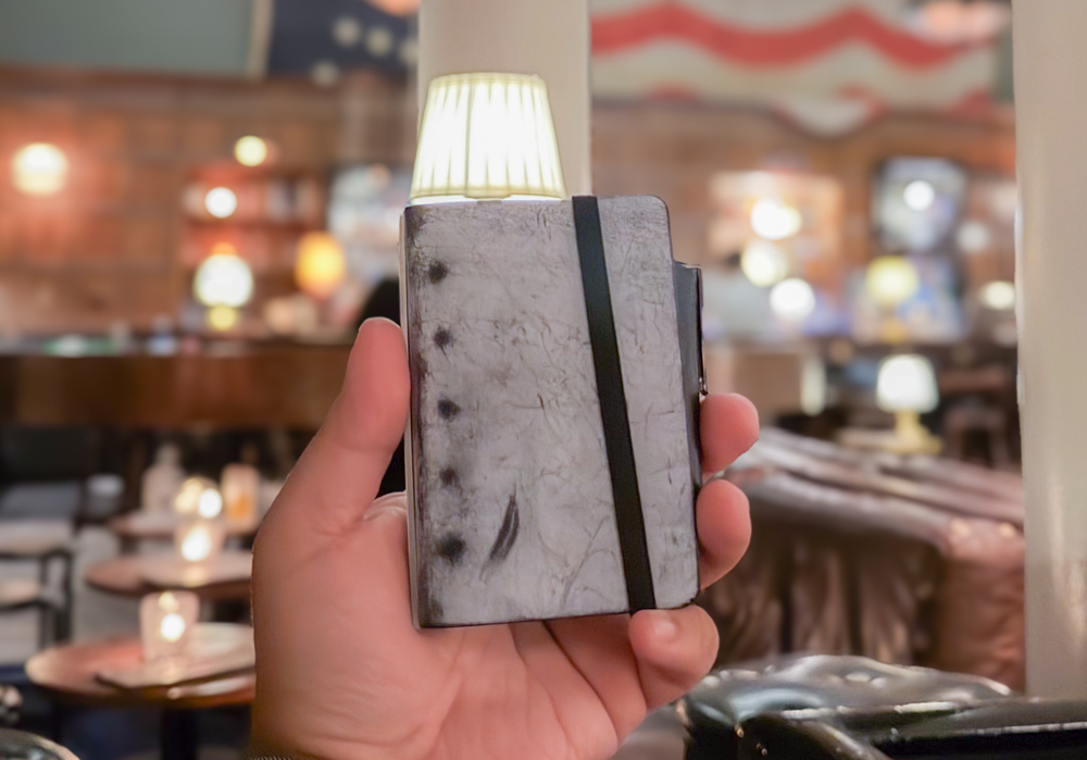 A person holding a mini 5 leather binder in shiranami leather from PLOTTER.