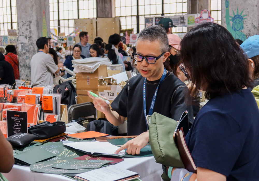 Takayuki Saito, the director of PLOTTER doing hand lettering and calligraphy on PLOTTER leather goods.