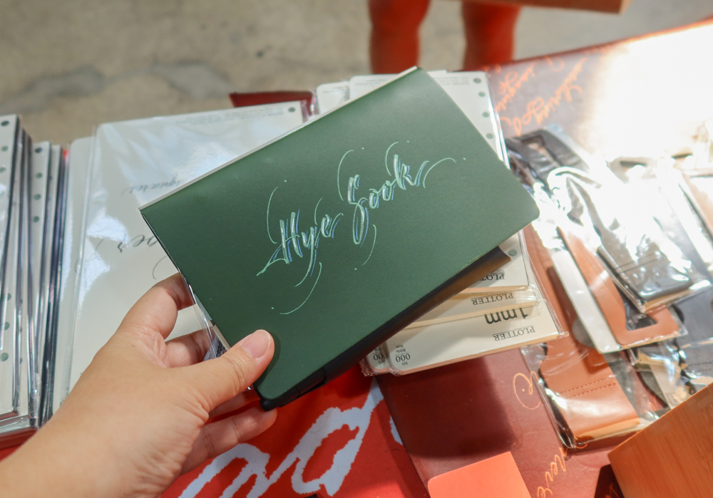 An example of Takayuki Saito's hand lettering on a green Roots leather binder from PLOTTER.